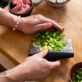 Kenji López-Alt uses an OXO bench scraper to scoop up sliced scallions